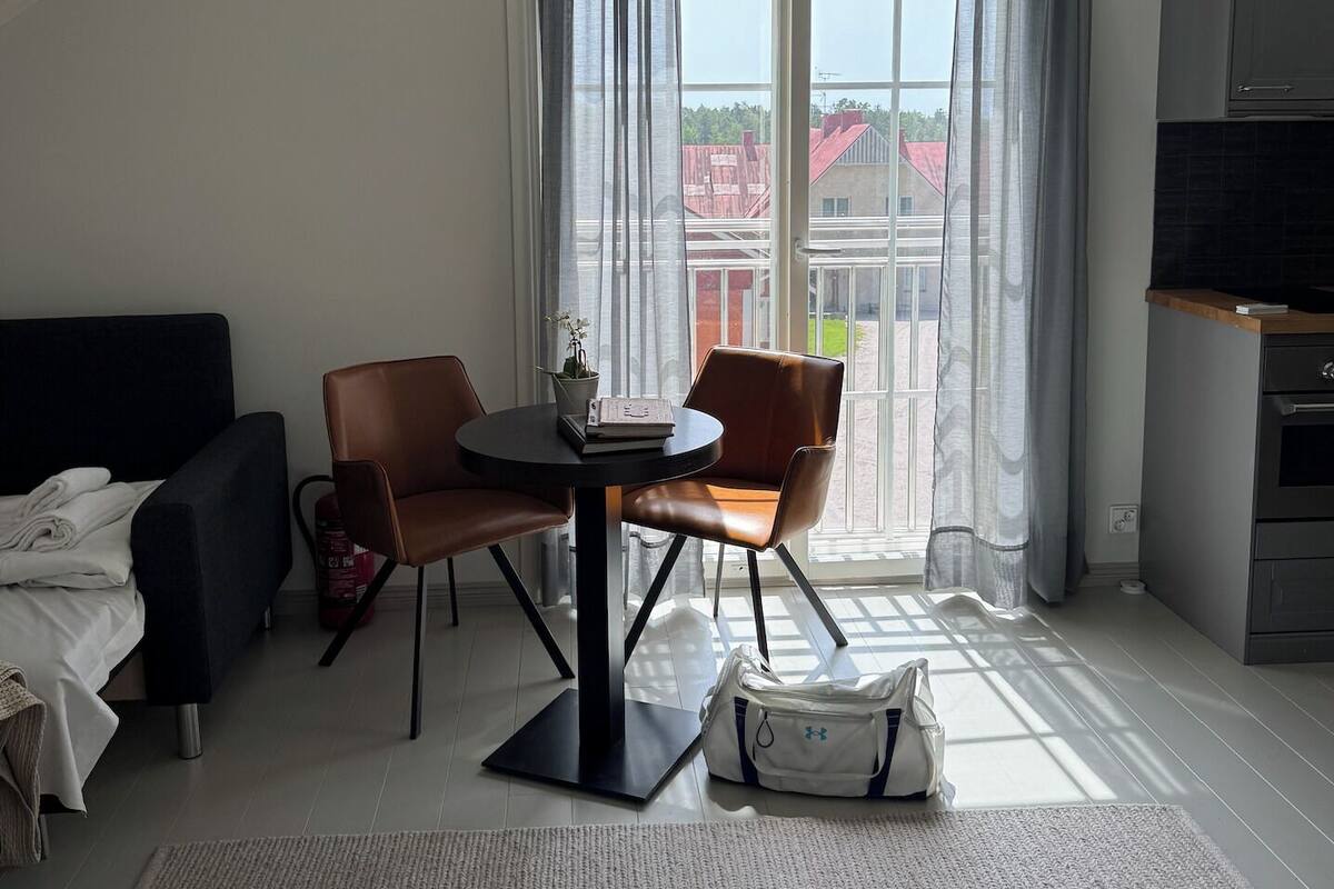 Una sala de estar moderna con comedor, ventanas amplias y vistas a edificios.