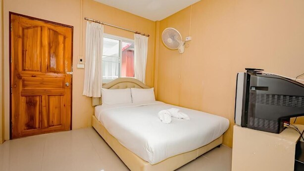 A bedroom with a bed, a wooden door, a window with curtains, a wall-mounted fan, and a television. - Rockwood house Resort and Thai massage (Phaya Yen)