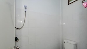 A small, white-tiled bathroom with a toilet, a shower, and a sink. - Rockwood house Resort and Thai massage (Phaya Yen)