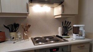Eine Küche mit Herd, Backofen, Kaffeemaschine und Kochgeschirr.