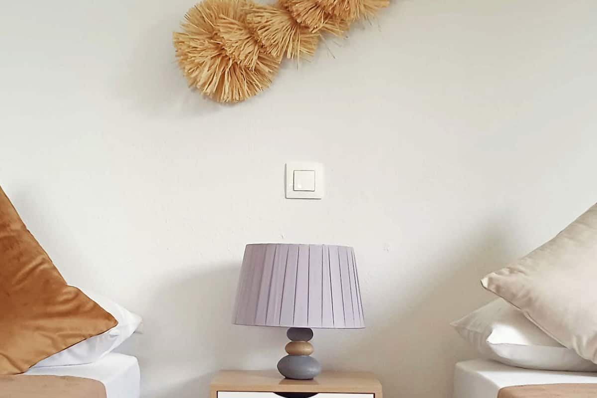 A bedroom with two beds, a nightstand with a lamp, and a wall decoration.