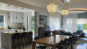 A modern kitchen with a central island, dining area with a wooden table and chairs, and a living room with a sofa and a TV. - Prestigious villa Loire Valley (Saint-Avertin)