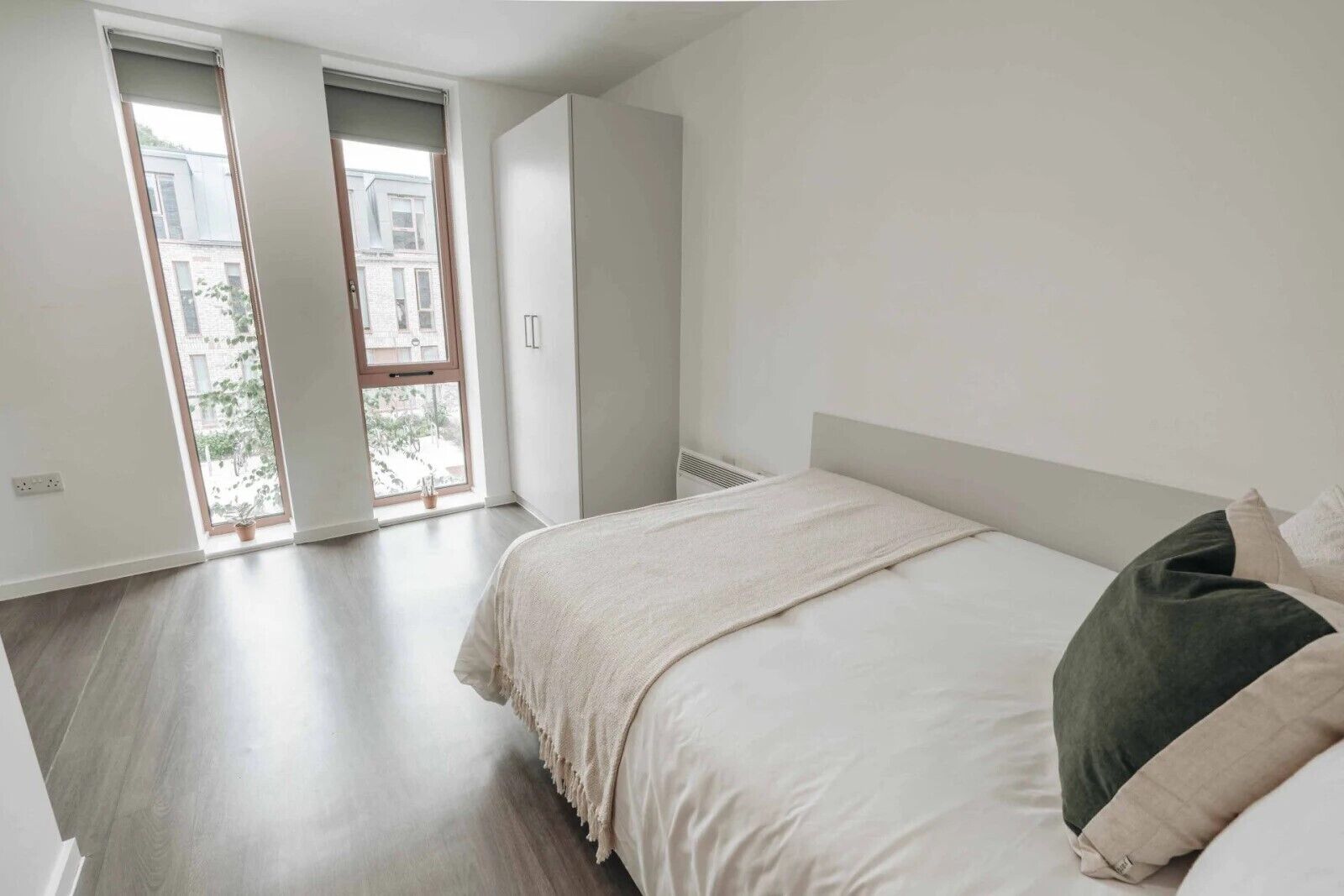 A bedroom with a large bed, a wardrobe, and a sliding door leading to a balcony.