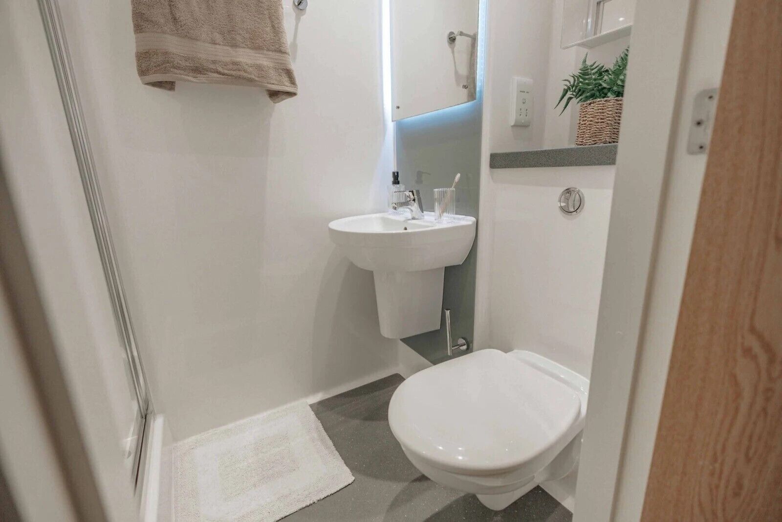 A small bathroom with a toilet, sink, and a towel hanging on the wall.