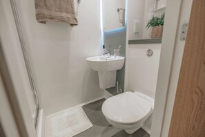 Uma casa de banho pequena com sanita, lavatório e toalha pendurada na parede.