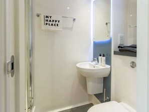 A modern bathroom with a white sink, a mirror, and a sign that reads "MY HAPPY PLACE".