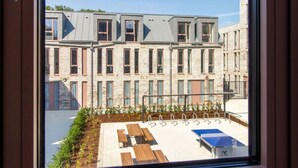 A view of a building with a courtyard, including a seating area with tables and a ping pong table. - Alma Court - Campus Accommodation (Canterbury)