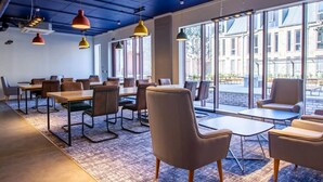 A modern conference room with large windows, a carpeted floor, and multiple tables and chairs. - Alma Court - Campus Accommodation (Canterbury)