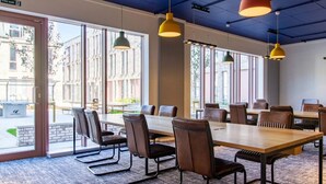 A conference room with large tables and chairs, large windows, and hanging pendant lights. - Alma Court - Campus Accommodation (Canterbury)