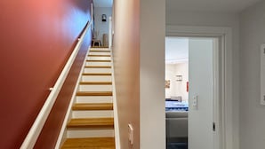 Eine Treppe mit Holzboden und weißen Geländern führt zu einem Zimmer mit einem Bett und einem Nachttisch.