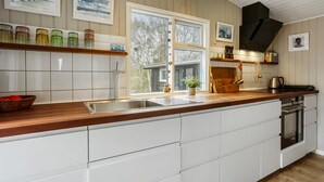 Una cocina moderna con armarios blancos, encimera de madera y un ventanal con vistas al exterior.