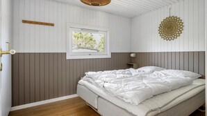 Una camera da letto con un letto, una finestra che si affaccia sul verde, un oggetto decorativo appeso al muro e un pavimento in legno.