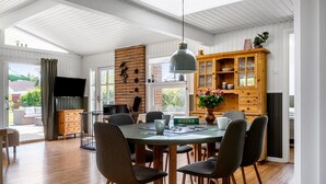 Zona pranzo con tavolo rotondo, sei sedie, un mobile in legno con vetrate e un lampadario.