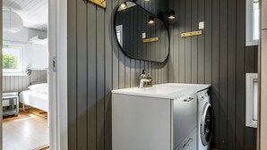Un bagno compatto con lavatrice integrata, lavandino e specchio.