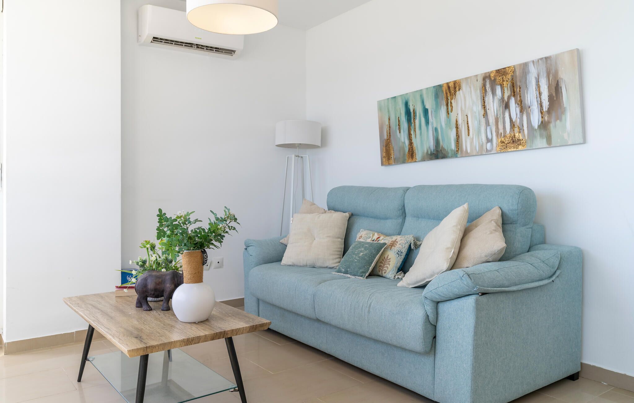 A living room with a light blue sofa, a wooden coffee table, and a floor lamp.