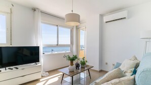 A modern living room with a TV, a coffee table with plants, a sofa, and a view of the sea. - Beach front apartment (San Luis de Sabinillas)