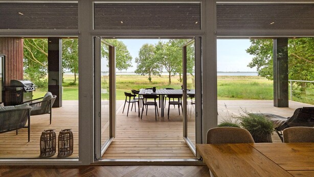 A modern outdoor dining area with a view of a grassy field and trees.