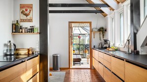 A kitchen with wooden cabinets, a black countertop, and a window overlooking a garden.