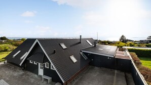 A modern house with a sloped roof, a small attached garage, and a view of the sea.