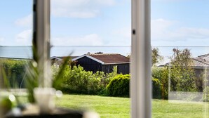 A view through a window of a house with a grassy yard and a body of water in the background.