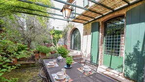 Eine Terrasse im Freien mit Esstisch, umgeben von Topfpflanzen und einer Ziegelwand.