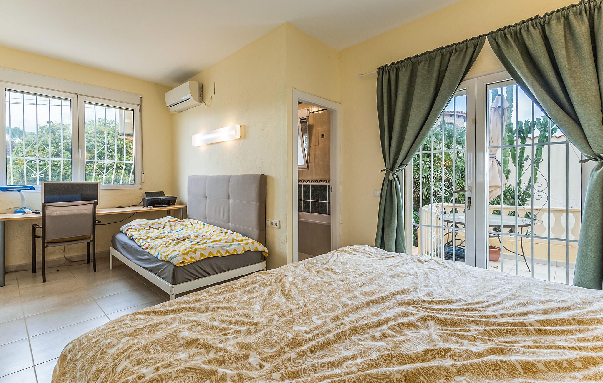 A bedroom with a bed, a desk, a chair, and a window with curtains.