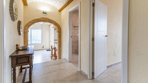 A hallway with a wooden table, chairs, and a coat rack. There are two doors, one leading to a bathroom and another to a bedroom. - Amazing home in Denia (Denia)