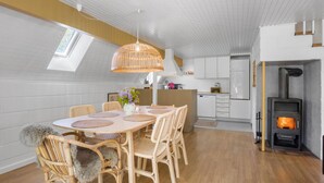 Ett modernt kök med vita skåp, en inbyggd spis och en matplats med ett runt bord och stolar i rotting.