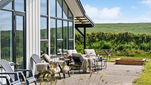 En terrasse med udendørs møbler, et bord og en træplantekasse.