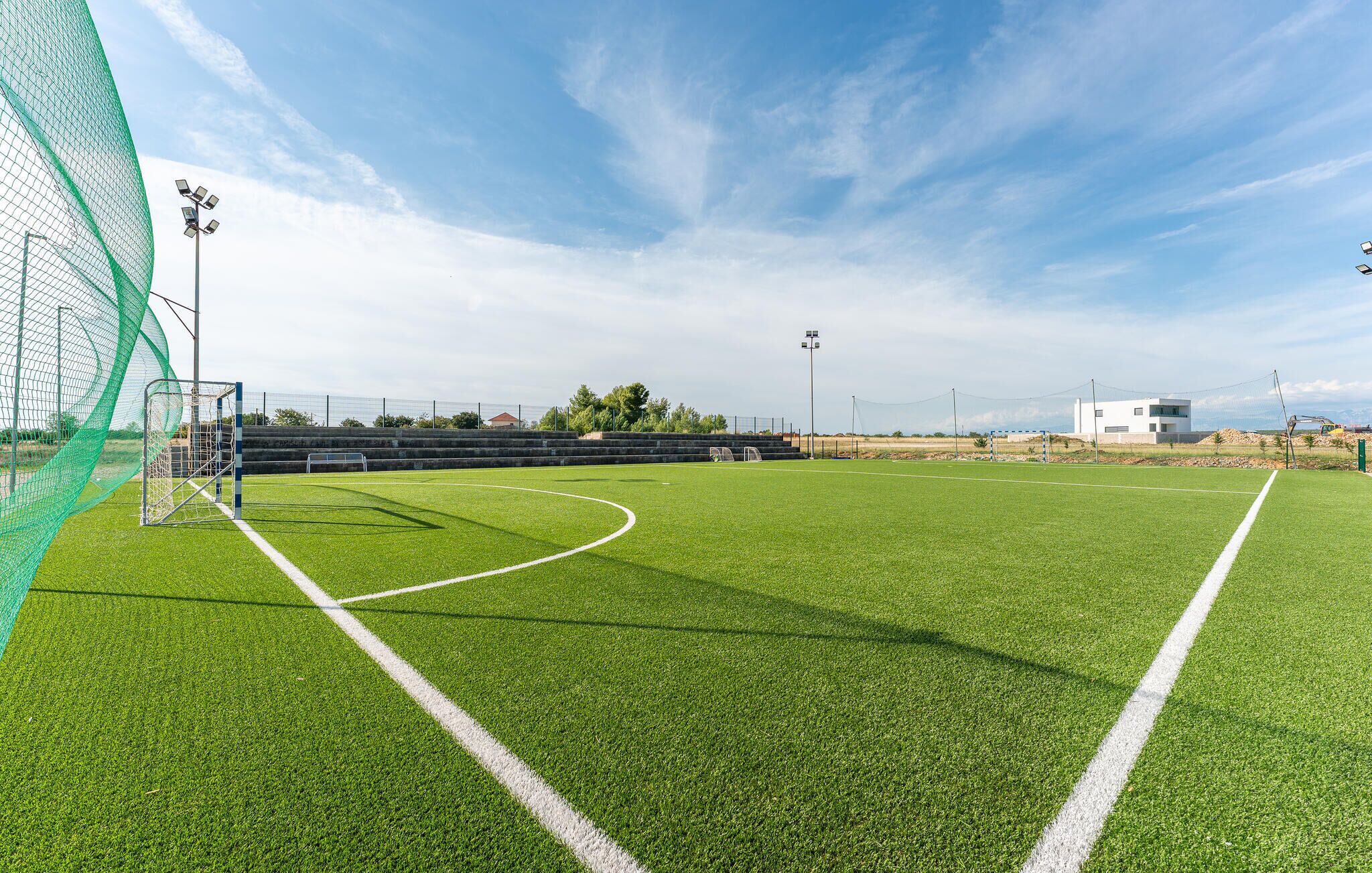 A soccer field with goalposts, floodlights, and bleachers.