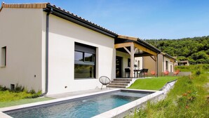 A modern house with a swimming pool, a covered patio, and a lush green landscape. - Lovely home in Puy St Martin (Puy St Martin)