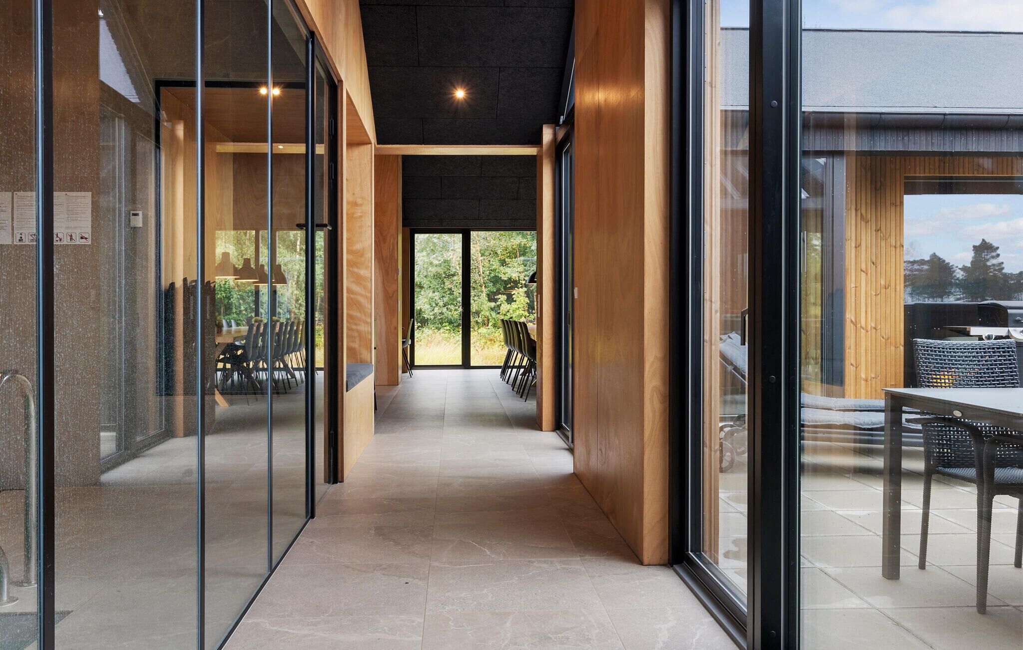 A modern interior with a glass partition, wooden accents, and a view of the outdoors.