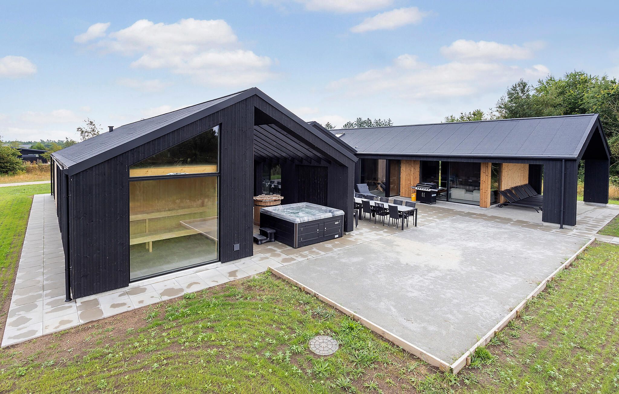 Un'area cucina esterna moderna con idromassaggio, barbecue e posti a sedere.