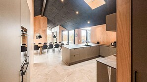 Een moderne keuken met een centraal eiland, een eethoek met stoelen, en een groot raam dat voor natuurlijk licht zorgt.