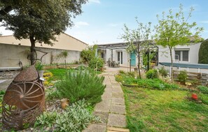 Stroll through the tranquil garden, surrounded by lush greenery and a rustic metal sculpture, with a seating area perfect for relaxation.