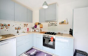 Compact kitchen with modern gas stove, oven, and sink, offering ample space for cooking and storage.