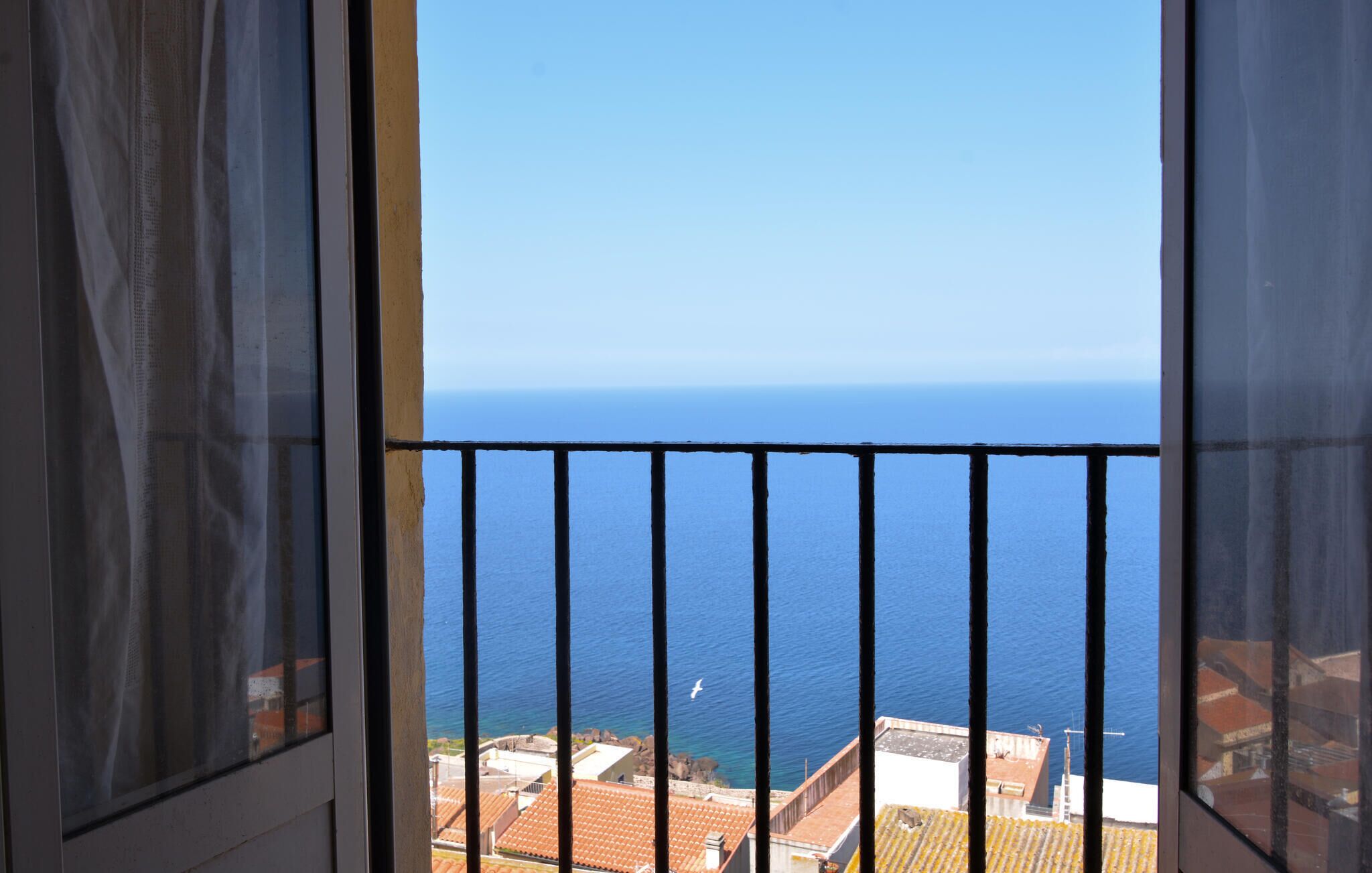 En balkon med udsigt til havet og bygninger.