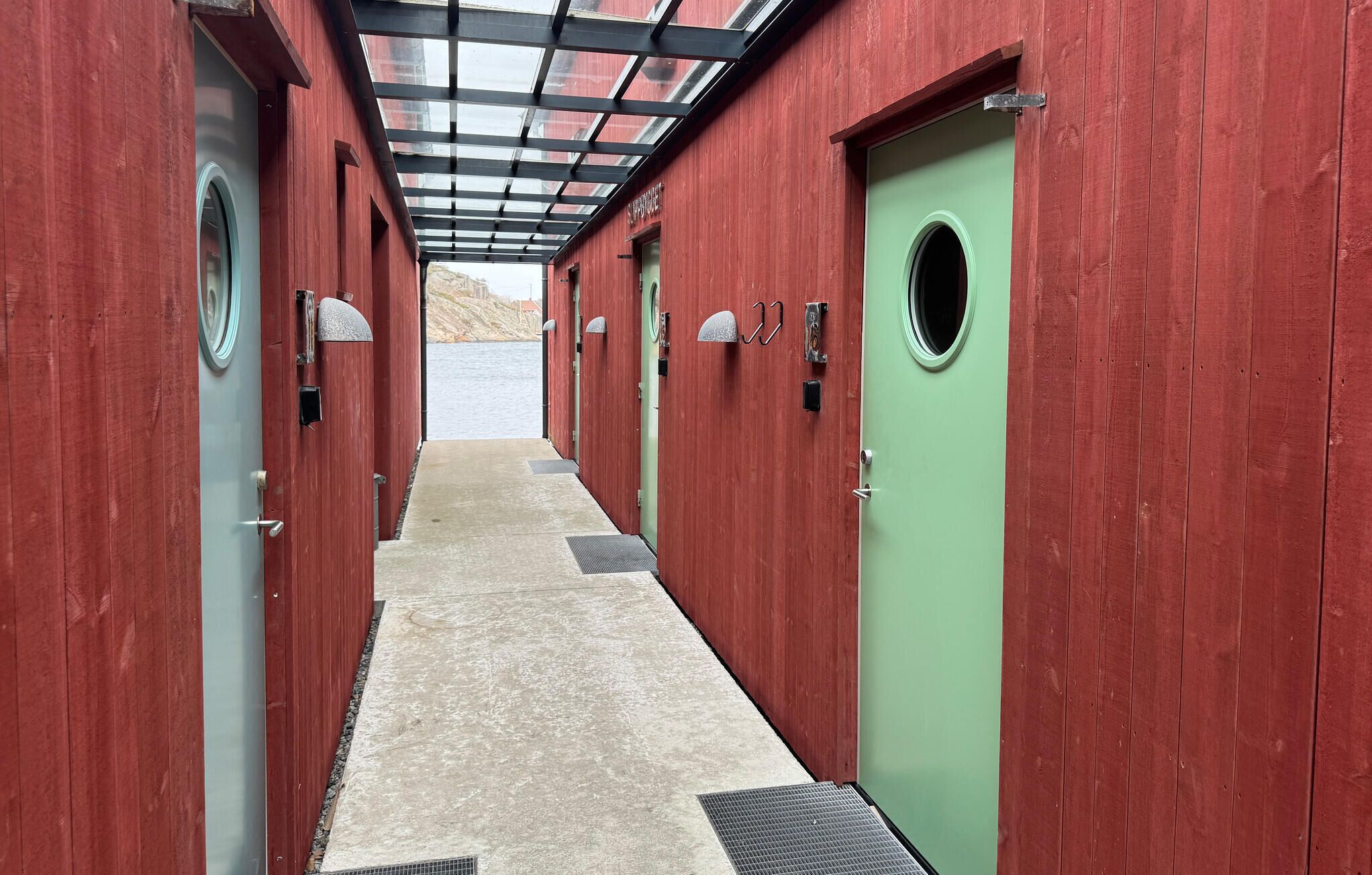 A corridor with red wooden walls, a green door, and a skylight.