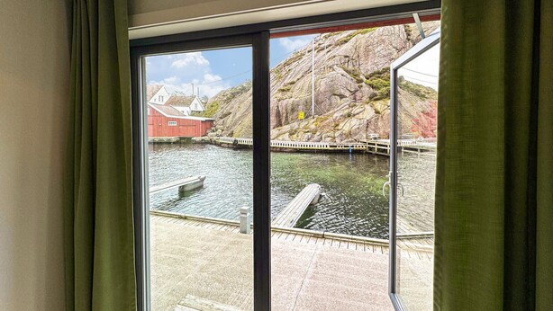 A view from a window overlooking a dock and a body of water with buildings in the background. - Pet friendly apartment in Søgne (Søgne)