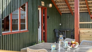 A wooden cabin with a dining area featuring a table, chairs, and a bowl of fruit.