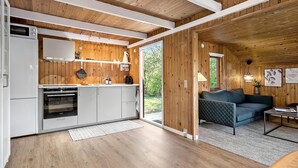 A modern kitchen with white appliances, wooden walls, and a large window.
