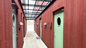A corridor with red walls, green doors, and a skylight.