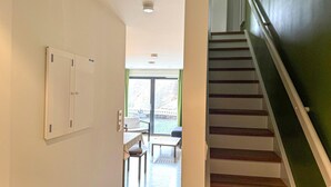 A hallway with a staircase leading to a balcony.