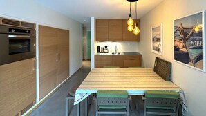 A modern kitchen with wooden cabinets, a built-in oven, and a dining area with a long table and chairs.