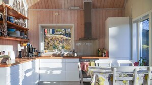 Una cocina moderna con armarios blancos, encimera de madera y ventana con vistas a un jardín.