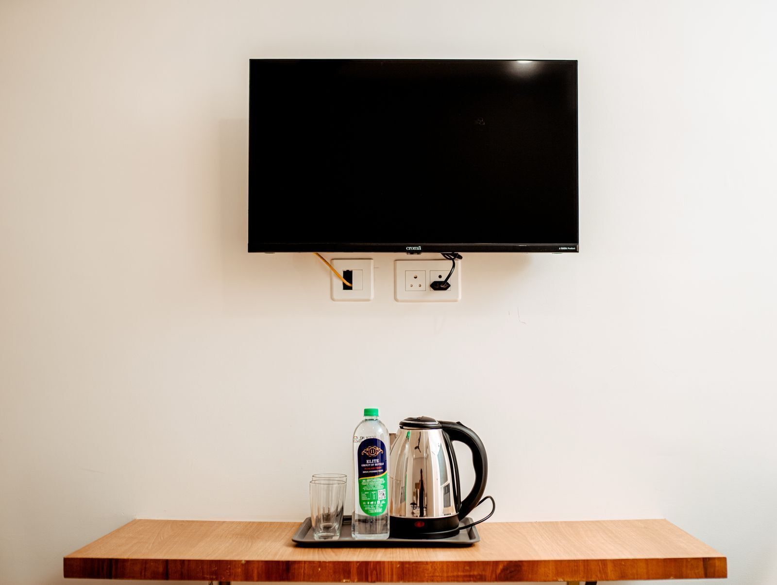 A television mounted on a wall with two power outlets below it.