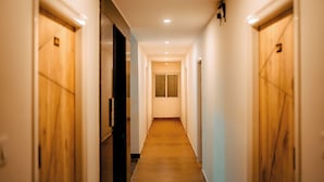 A narrow, well-lit hallway with wooden doors on both sides, leading to a room with a window. - Hotel Elite Fortune Inn (Tirupati)