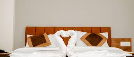 A neatly made bed with a heart-shaped towel arrangement on the bedspread.
