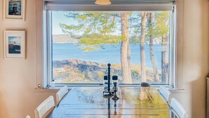 A dining table with a view of the sea and trees through a large window. - Beautiful home in Lysekil (Lysekil)