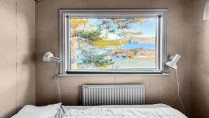 A bedroom with a bed, a window with a view of trees and a body of water, and a radiator below the window. - Beautiful home in Lysekil (Lysekil)